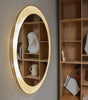 A round ATBO designer FLORIS WALL MIRROR is hanging on a wall next to a bookcase.