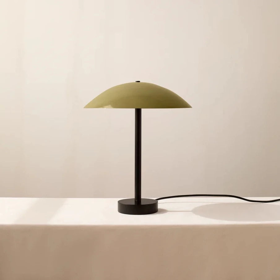 An innovative ARUNDEL TABLE LAMP by IN COMMON WITH beautifully enhancing the aesthetics of a white table with its vibrant green hue.