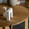 A wooden table with a white letter on top and a KRISTINA DAM STUDIO BRICK SCULPTURE.