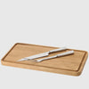 A minimalist design wooden cutting board with STELTON SIXTUS CARVING KNIFE utensils.