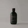 A bottle of Manisante Oud Shampoo for gentle cleansing on a grey background.