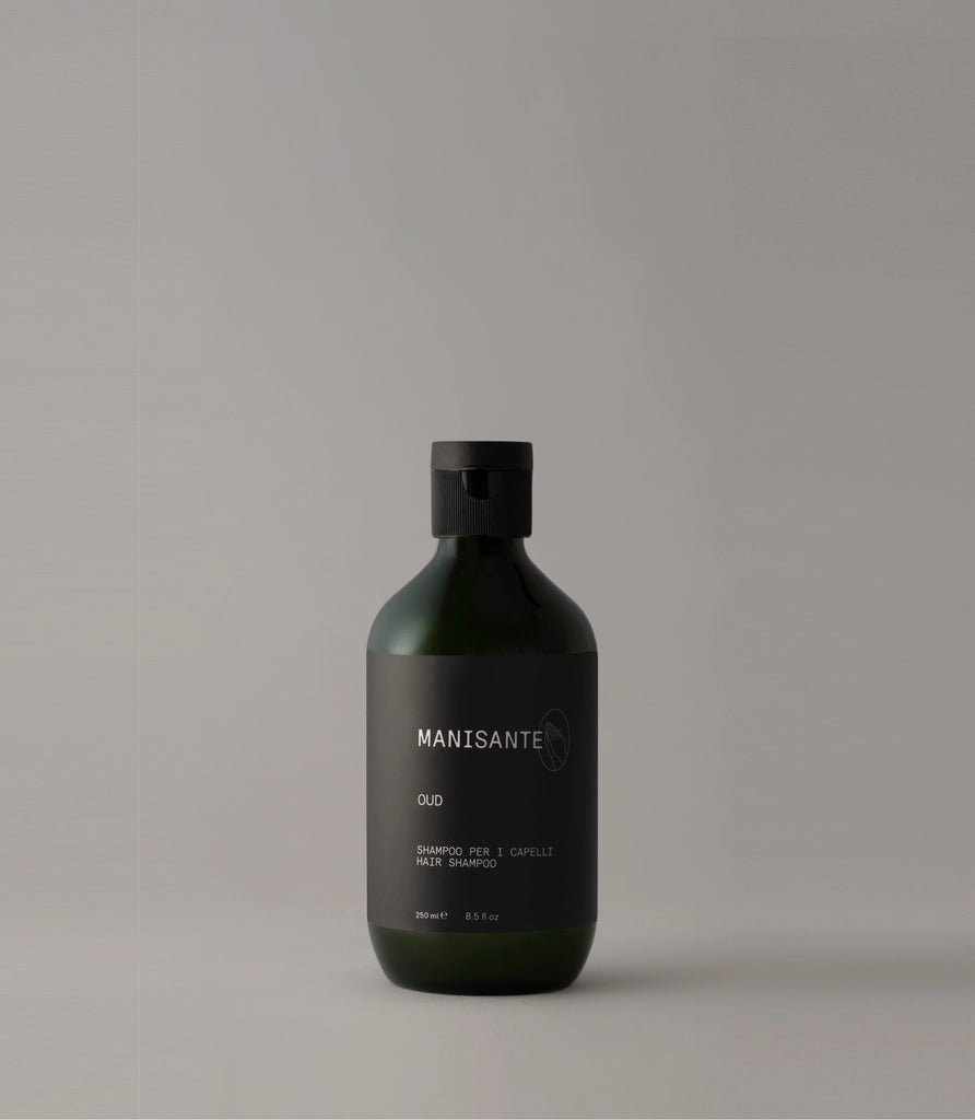 A bottle of Manisante Oud Shampoo on a grey background.