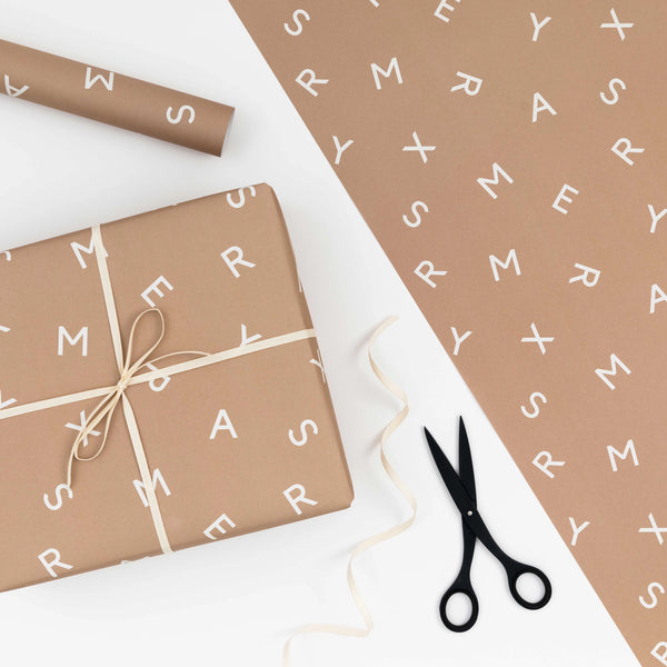A MERRY XMAS TYPE GIFT WRAP by KINSHIPPED with scissors and a bow.