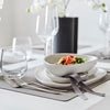A table setting with white plates and flowers featuring LIND DNA SQUARE DINNER MATS made from recycled leather.