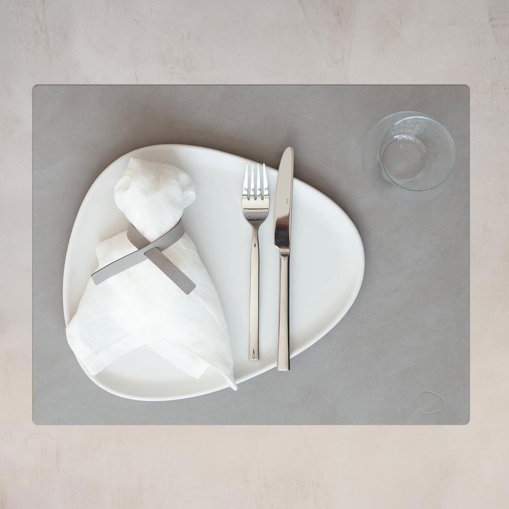 A white plate with a knife and fork on it featuring an OEKO-TEX® recycled leather SQUARE DINNER MAT by LIND DNA.