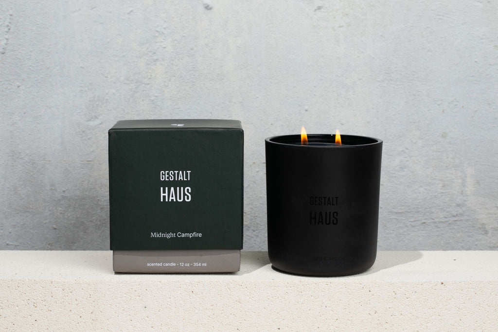 A MIDNIGHT CAMPFIRE CANDLE imbued with the enchanting aroma of smoked wood, accompanied by a small box beside it. (Brand: GESTALT HAUS)