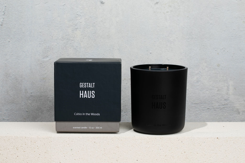 A Cabin in the Woods candle by Gestalt Haus, with a box next to it, emitting the enchanting scent of Vetiver.
