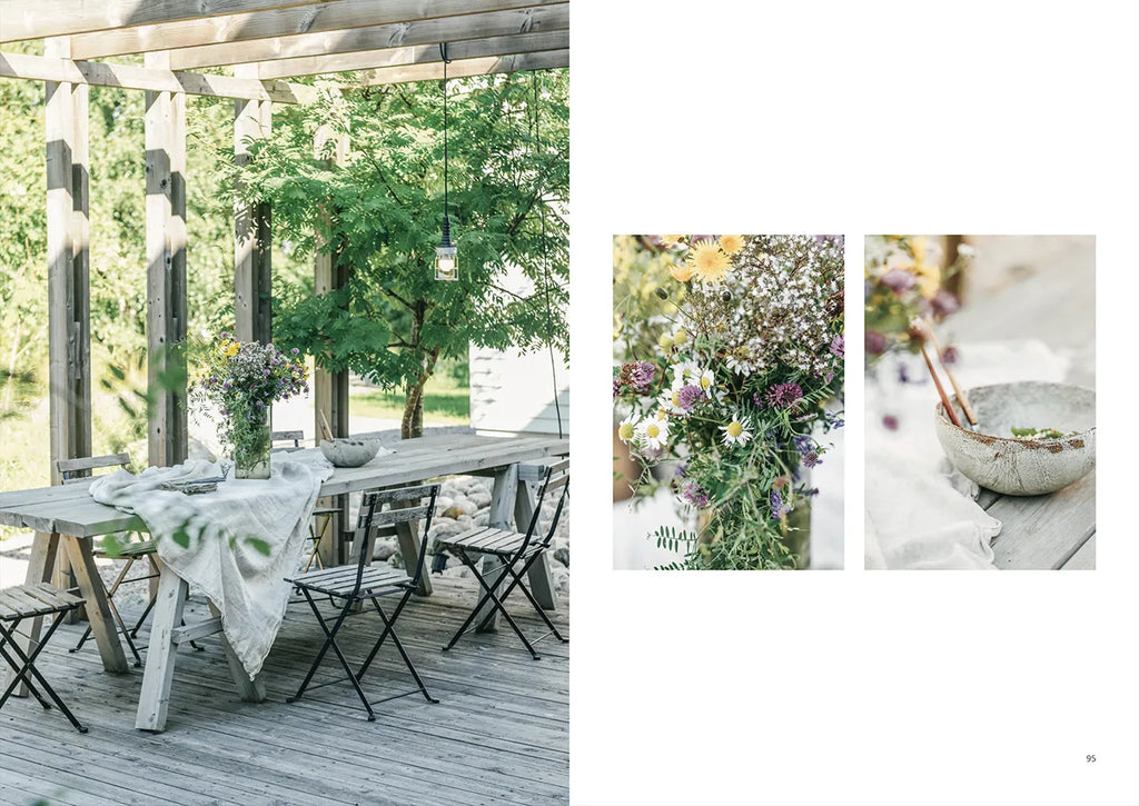 A OUTDOOR CHIC table and chairs on a wooden deck with flowers in vases. (Brand: COZY)