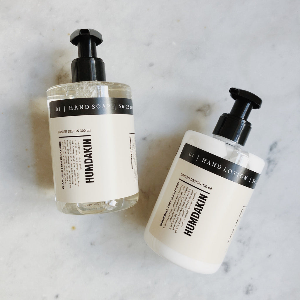 Two bottles of HUMDAKIN's 01 HAND LOTION SEA BUCKTHORN + CHAMOMILE on a marble countertop.