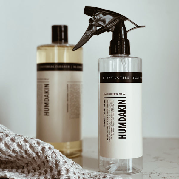 A refillable spray bottle of Humdakin Universal Cleaner and a towel on a counter.