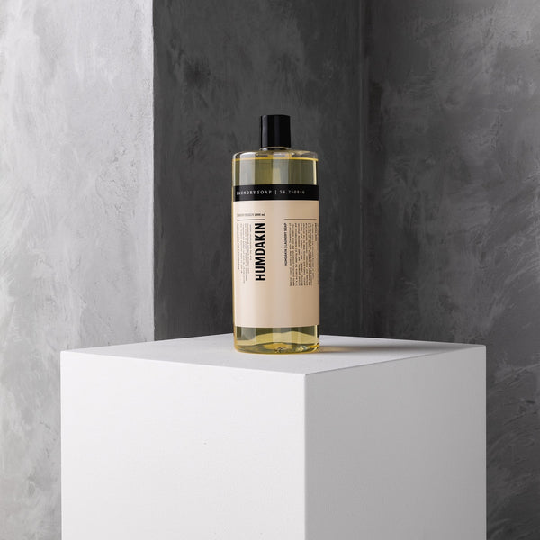 A bottle of HUMDAKIN 01 LAUNDRY SOAP CHAMOMILE + SEA BUCKTHORN with natural extracts sitting on top of a concrete pedestal.