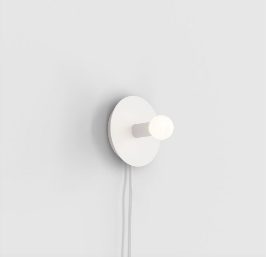 A white DOT WALL LAMP by LAMBERT ET FILS with a bulb on it, designed in the minimalist style of Gestalt Haus.
