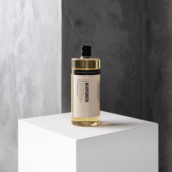 A bottle of Humdakin 01 Universal Cleaner Salia + Sea Buckthorn sitting on top of a white cube, used for cleaning surfaces.