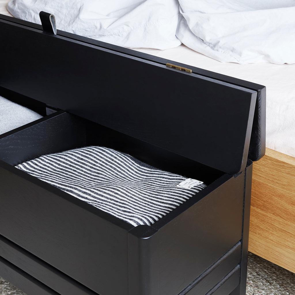 A bed with a FORM & REFINE LINE STORAGE BENCH 111 on top of it.
