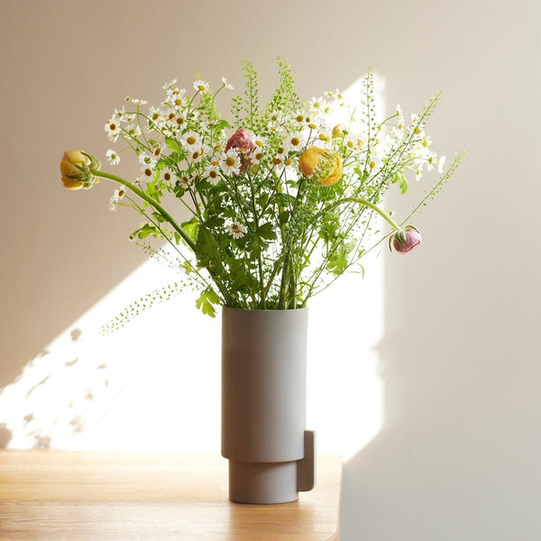 An ALCOA VASE filled with flowers sitting on a table by FORM & REFINE, inspired by the concept of Gestalt Haus.