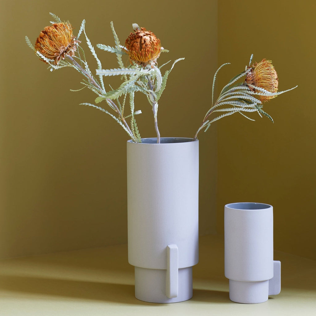 Two FORM & REFINE ALCOA vases showcasing flowers on a vibrant yellow table.