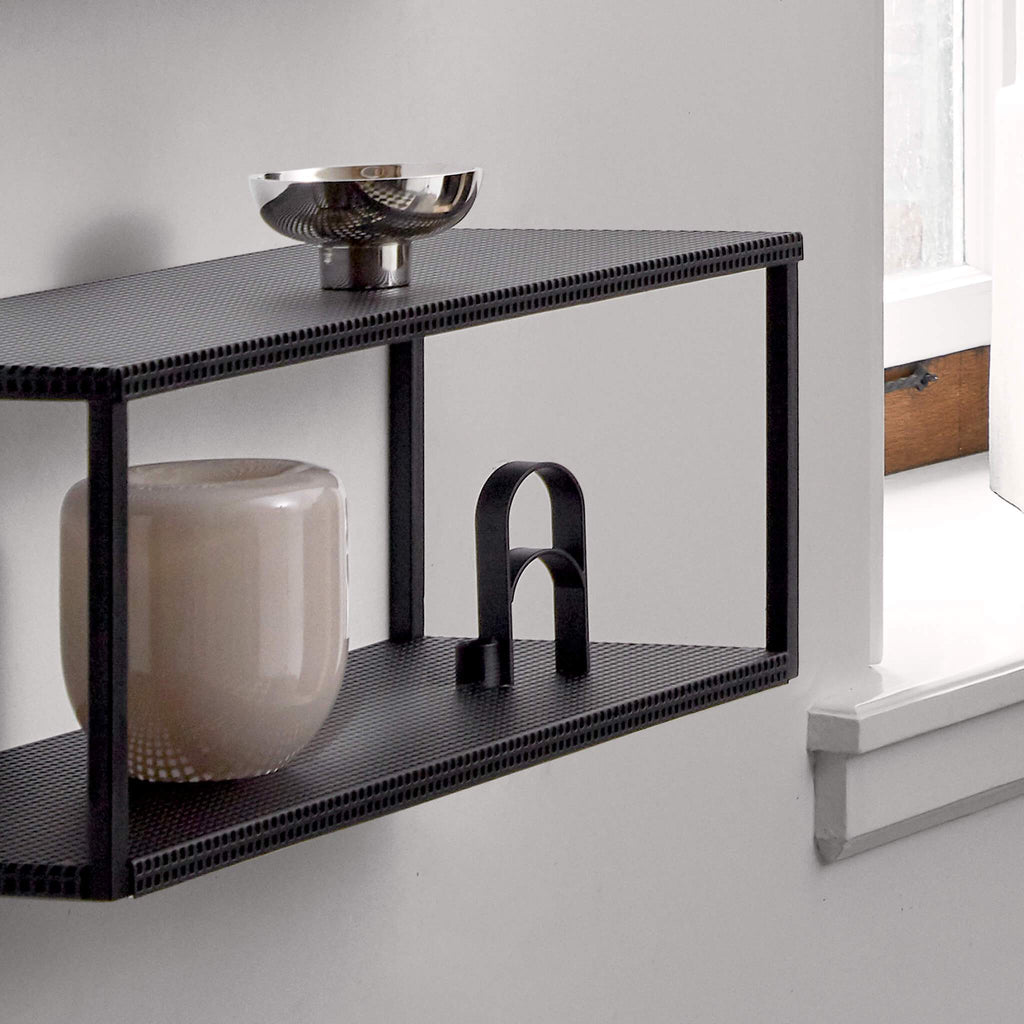 A black TEALIGHT CANDLEHOLDER from KRISTINA DAM STUDIO with a vase on it.