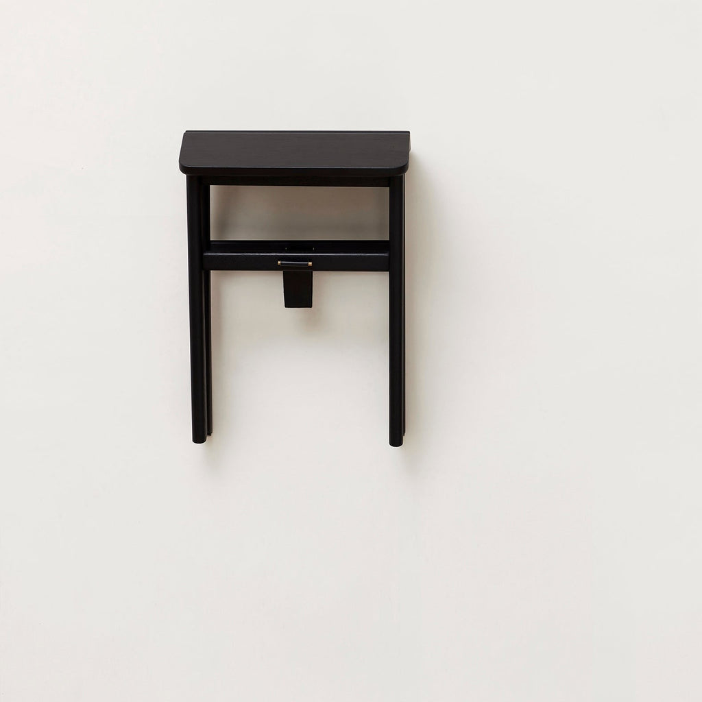 A small black FORM & REFINE ANGLE FOLDABLE STOOL against a white wall in the Gestalt Haus.
