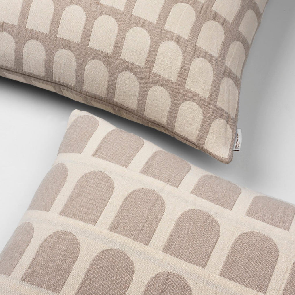 A pair of ARCH CUSHION COVER pillows with arches on them by KRISTINA DAM STUDIO, inspired by Gestalt principles.