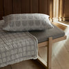 A wooden bed with a Kristina Dam Studio ARCH CUSHION COVER featuring Gestalt design.