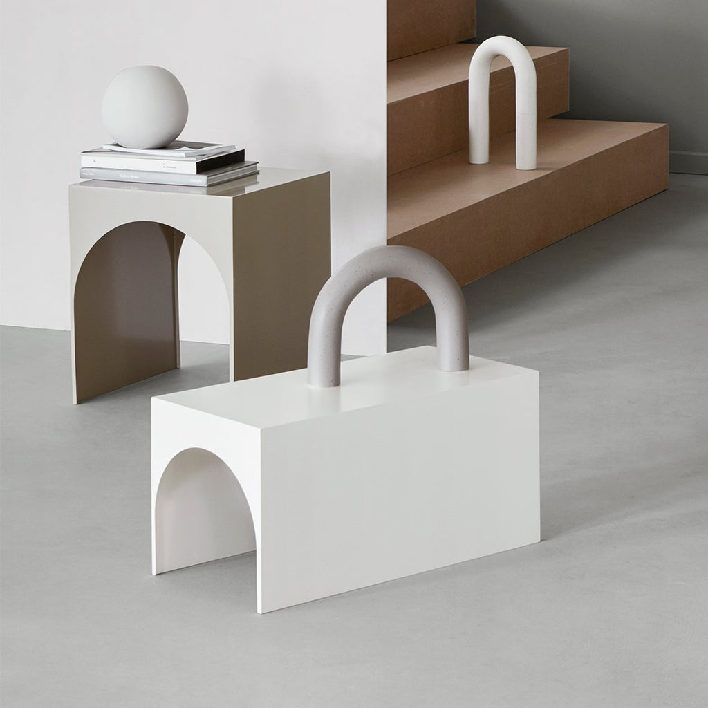 A small white ARCH TABLE from KRISTINA DAM STUDIO with a white object showcasing Gestalt Haus on top of it.