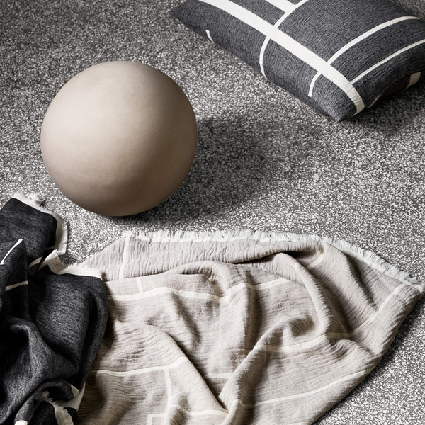 An ARCHITECTURE THROW and a pillow on the floor, creating a cozy Gestalt Haus ambiance.