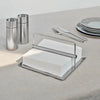 A Gestalt Haus-themed napkin holder holding silverware and napkins on a table.