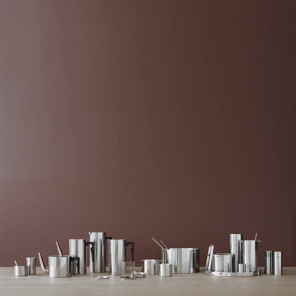 A group of REVOLVING ASHTRAYS by STELTON on a table in front of a brown wall.