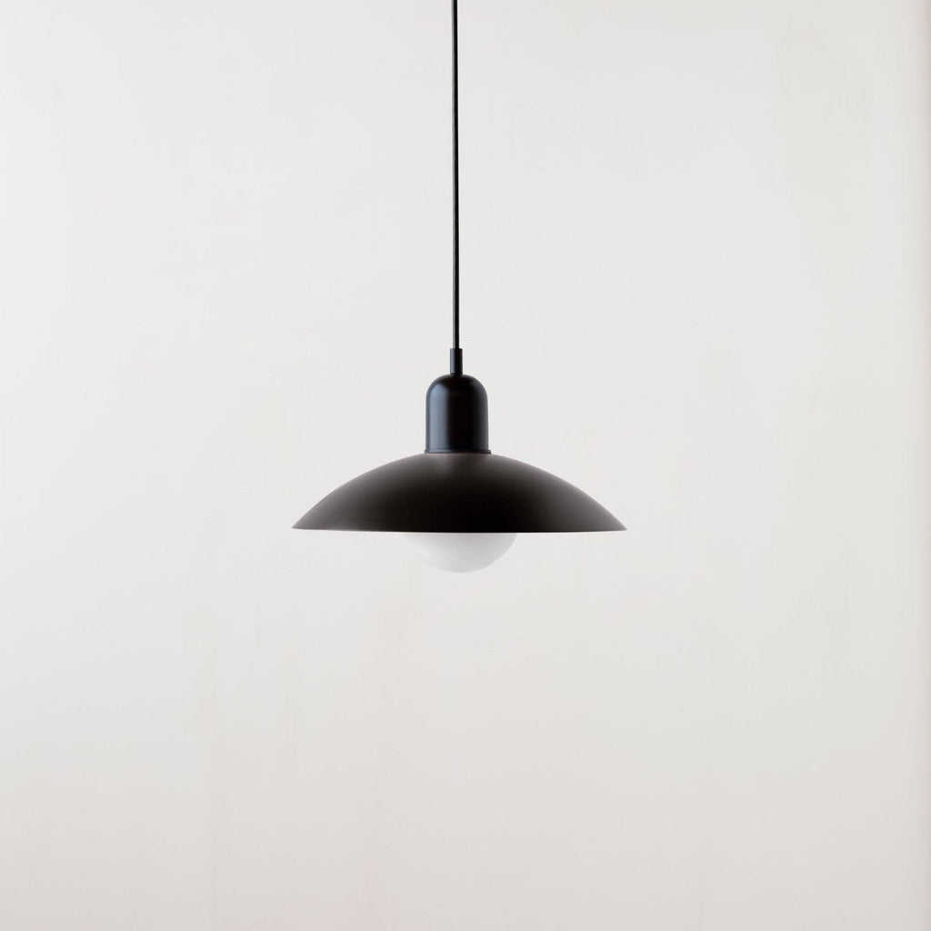 An Arundel Orb Pendant hanging from a white wall, inspired by Gestalt Haus design.