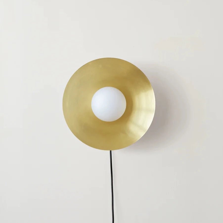 An ARUNDEL ORB SURFACE MOUNT wall lamp by IN COMMON WITH enhances the ambiance of a white wall.