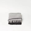 A AYMARA PLAID THROW by FORM & REFINE, with fringes in grey and black, from Gestalt Haus.