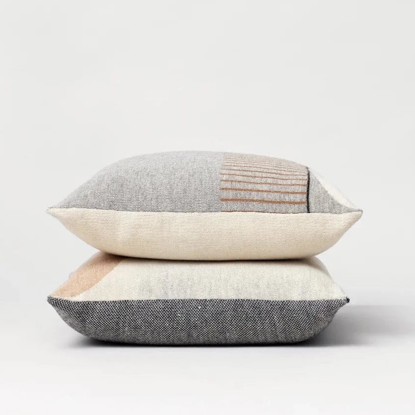 Two AYMARA SQUARE CUSHIONS by FORM & REFINE, grey and beige, stacked on top of each other in Gestalt Haus.