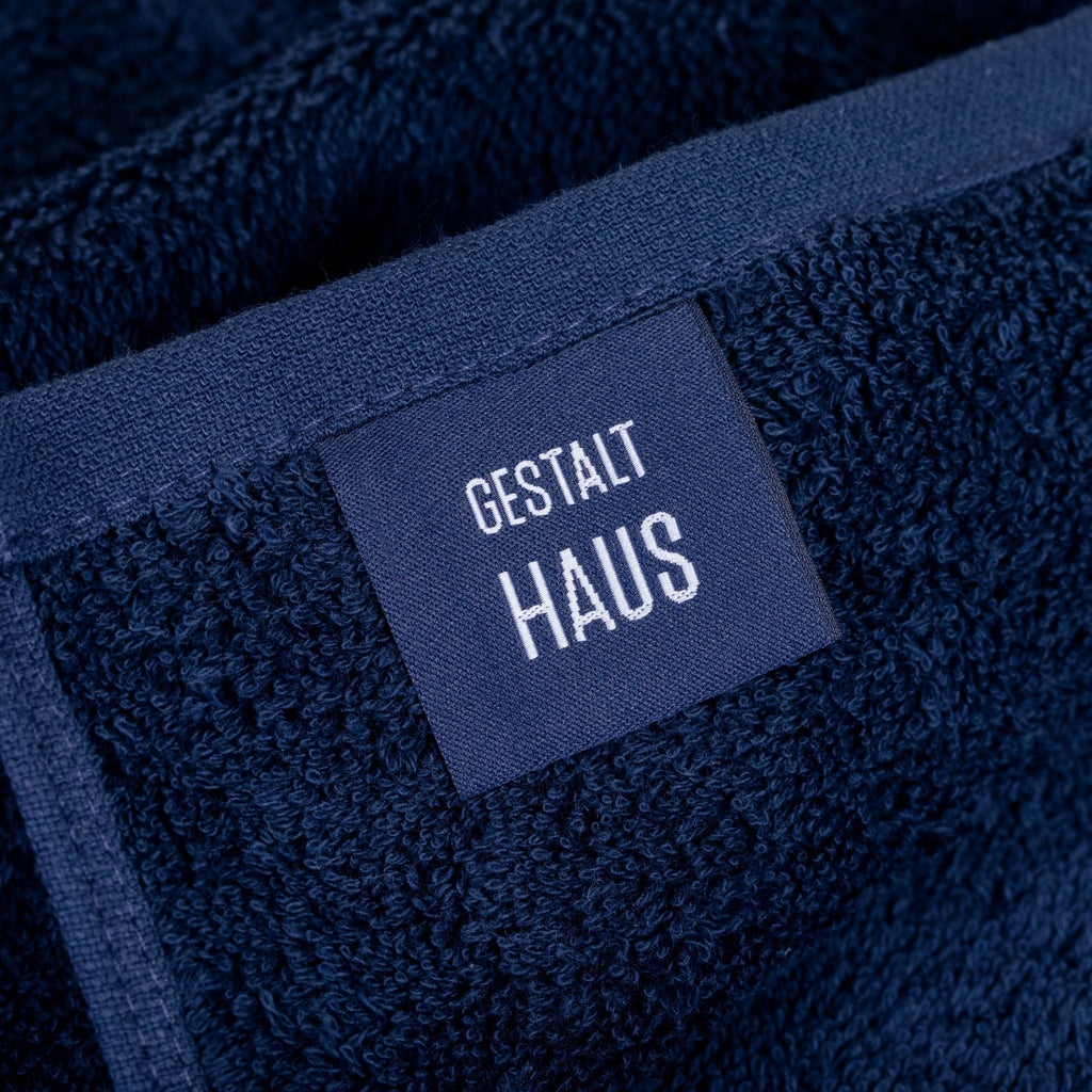 A blue BATH SHEET with a label that says GESTALT HAUS.