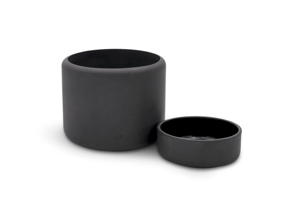 A black BOTANY PORCELAIN PLANT POT by AARON PROBYN and a black bowl on a white surface in the Gestalt Haus.