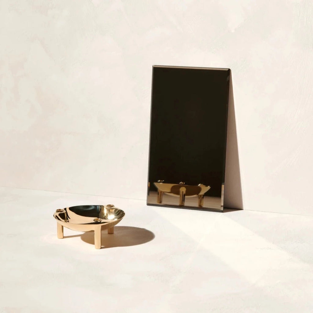 A STOFF NAGEL gold bowl and mirror on a white surface inside the Gestalt Haus.