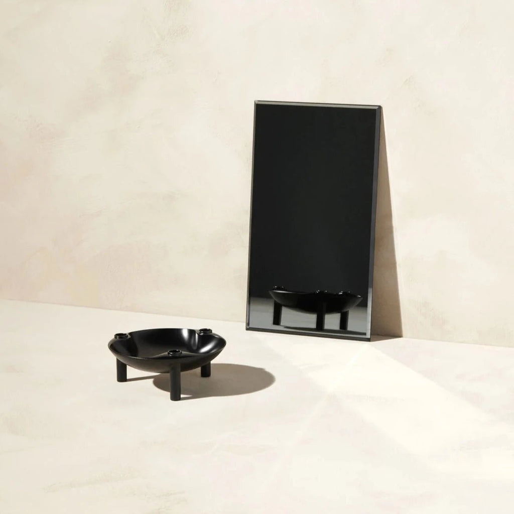 A black STOFF NAGEL bowl sits on a table next to a mirror in the Gestalt Haus.