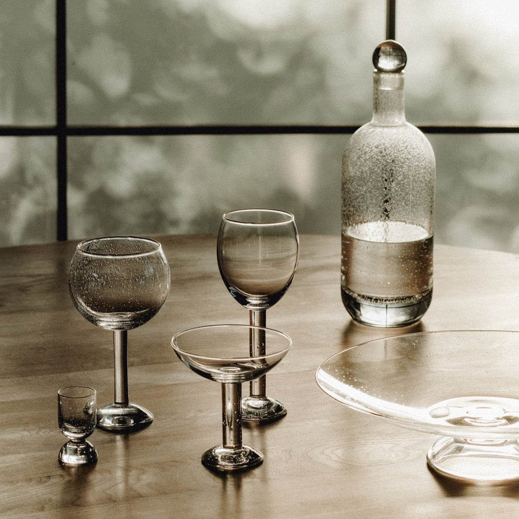 A grouping of LOUISE ROE BUBBLE GLASS CARAFE and a bottle on a Gestalt Haus table.