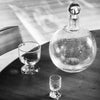 A black and white photo of a Louise Roe Bubble Glass Carafe and a glass on a table at Gestalt Haus.