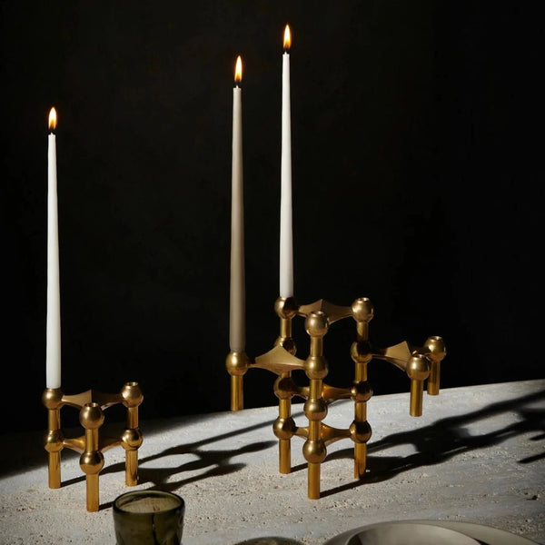 A set of STOFF NAGEL brass CANDLE HOLDERS on a Gestalt Haus table.