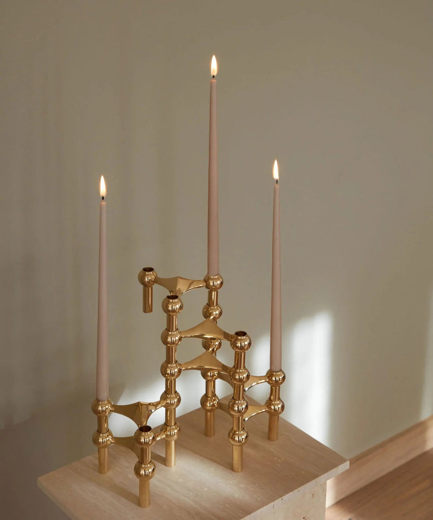 A Gestalt Haus candle holder with three candles sitting on top of a wooden base.