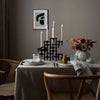 A table setting featuring STOFF NAGEL candle holders and a vase of flowers, inspired by Gestalt Haus aesthetics.