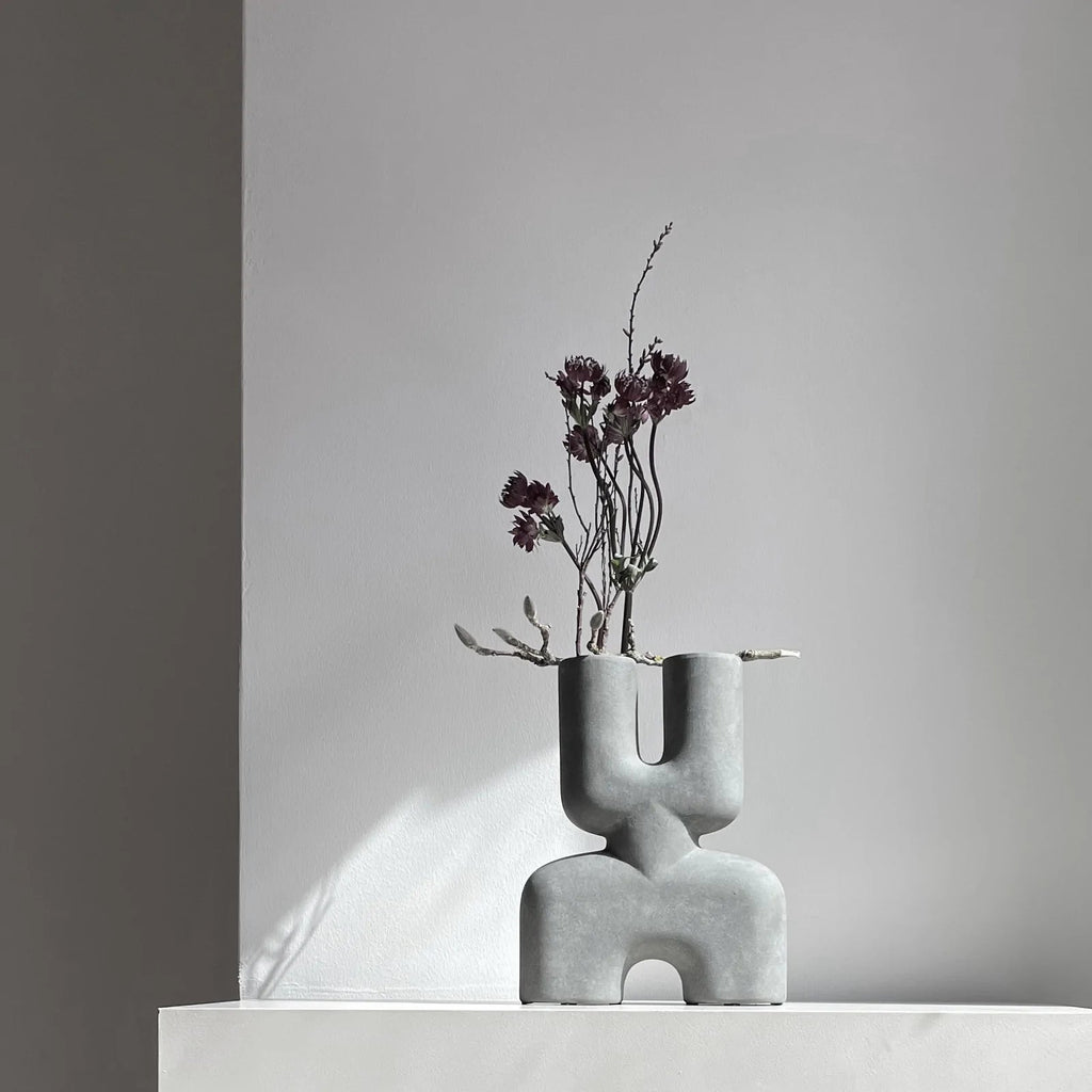 A COBRA DOUBLE SCULPTURES vase with flowers sitting on top of a white table, branded by 101 COPENHAGEN.