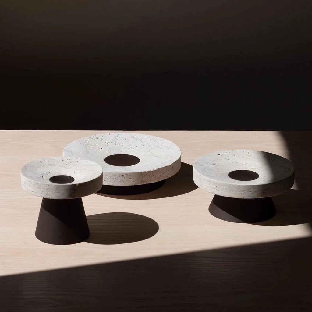 Three COLISEU PEDESTALS candle holders on a wooden table.