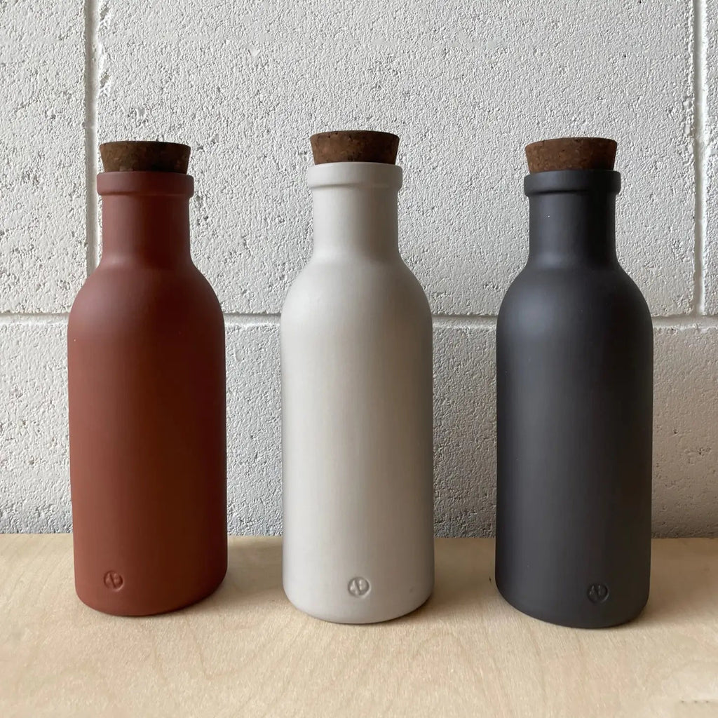 Three different colored Colombo Porcelain bottles with natural cork on a wooden table from Gestalt Haus.