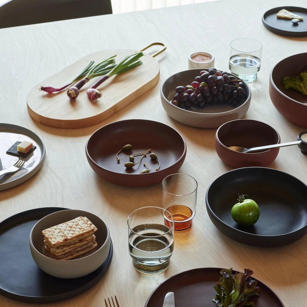 A COLOMBO TABLEWARE table with a variety of plates and bowls on it, designed by AARON PROBYN for Gestalt Haus.
