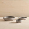 Three grey Gestalt Haus COLOMBO TABLEWARE bowls on a wooden table. Brand name: AARON PROBYN.