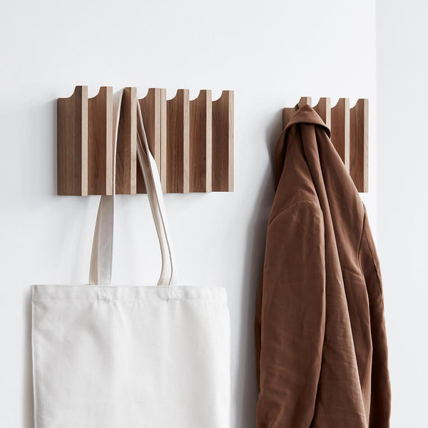 A COLUMN COAT RACK with a tote bag hanging on it, designed by Kristina Dam Studio.
