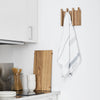 A white kitchen with a column coat rack hanging on the wall.
