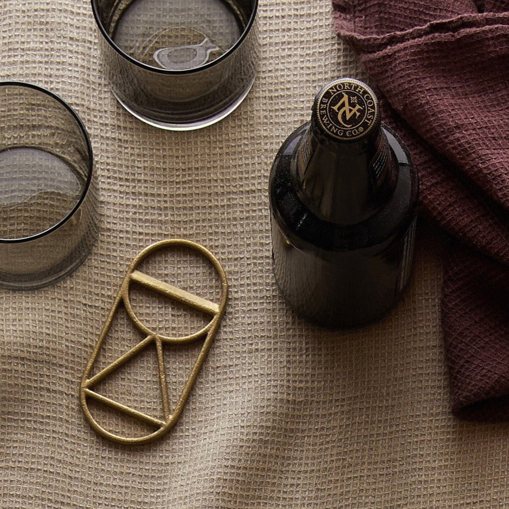 A bottle of wine, a glass, and a CREST BOTTLE OPENER from FS OBJECTS.