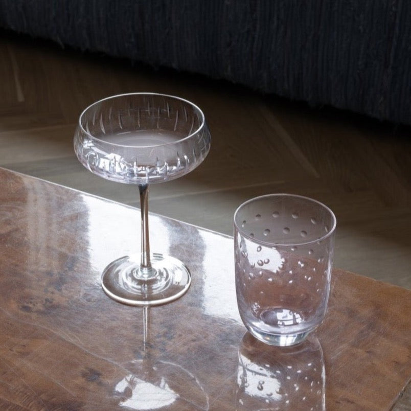 A coffee table with a crystal champagne coupe by Gestalt Haus on it.
